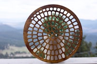 a circular wooden plate sitting on a table with mountains in the background