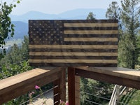 an american flag on a wooden deck with mountains in the background